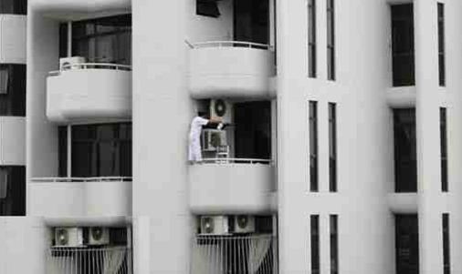 barefoot man on balcony with A/C