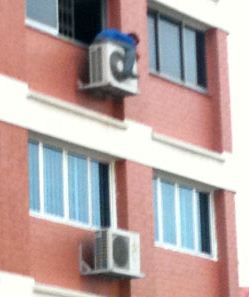 person hugging aircon unit up high
